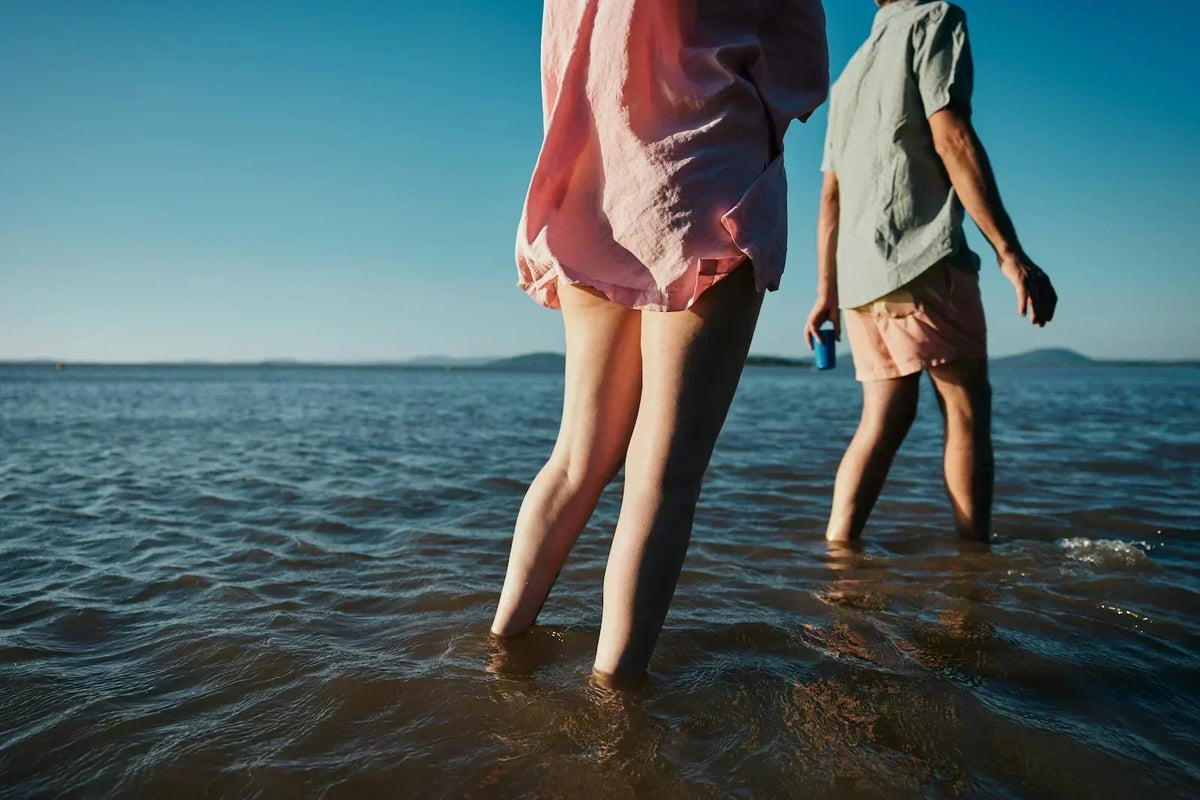 Couple walking together in shallow water at sunset, illustrating how PMDD affects relationship dynamics.