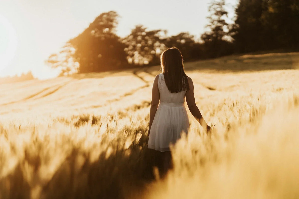 Young woman walking through a sunlit field, illustrating how early PMDD symptoms can be easy to miss.